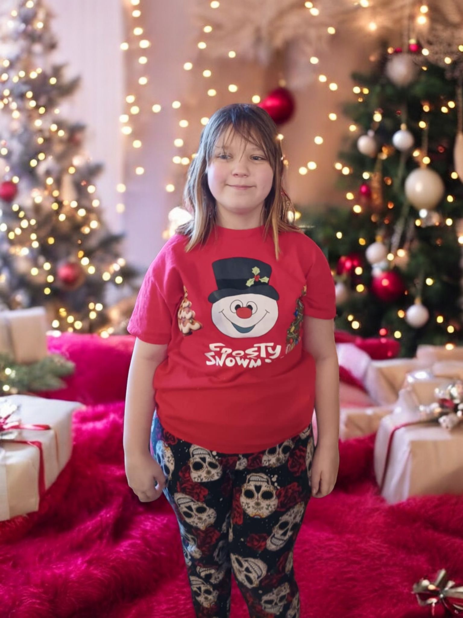A person in a red snowman shirt and skull-print pants stands in a room with Christmas trees and wrapped presents.
