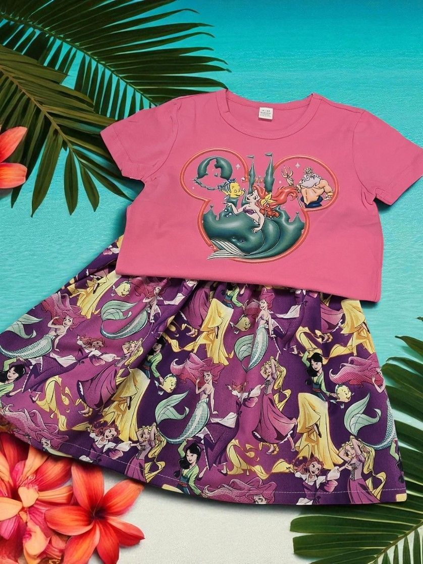 A pink shirt with a Disney-themed Mickey silhouette print paired with a purple skirt featuring an all-over mermaid pattern.