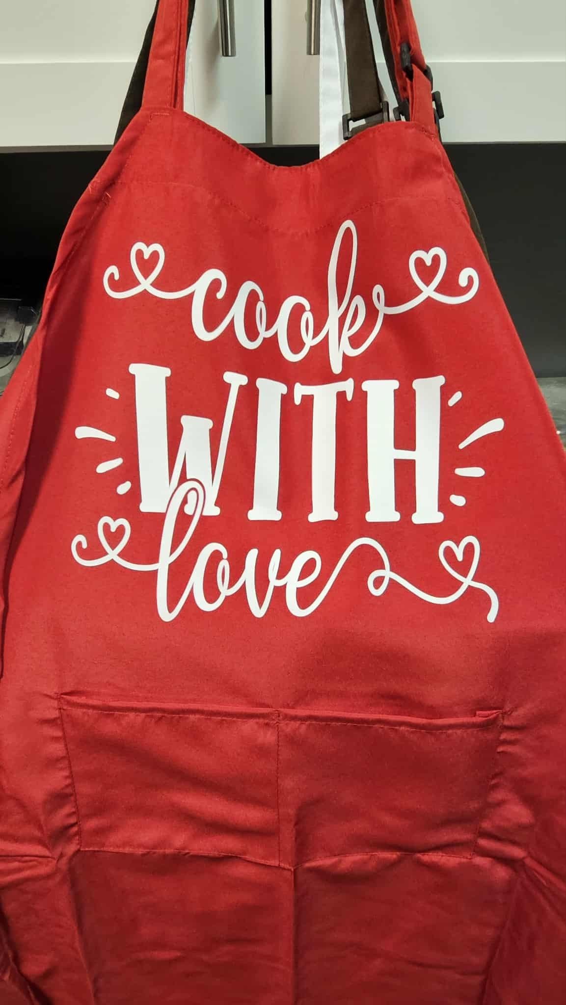 A red apron with a large pocket and white text that reads 