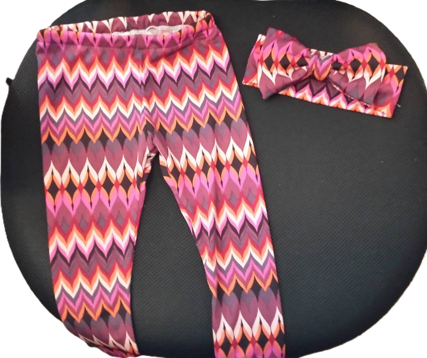 Leggings and a matching knotted headband in a vibrant, multicolored zigzag and diamond pattern.