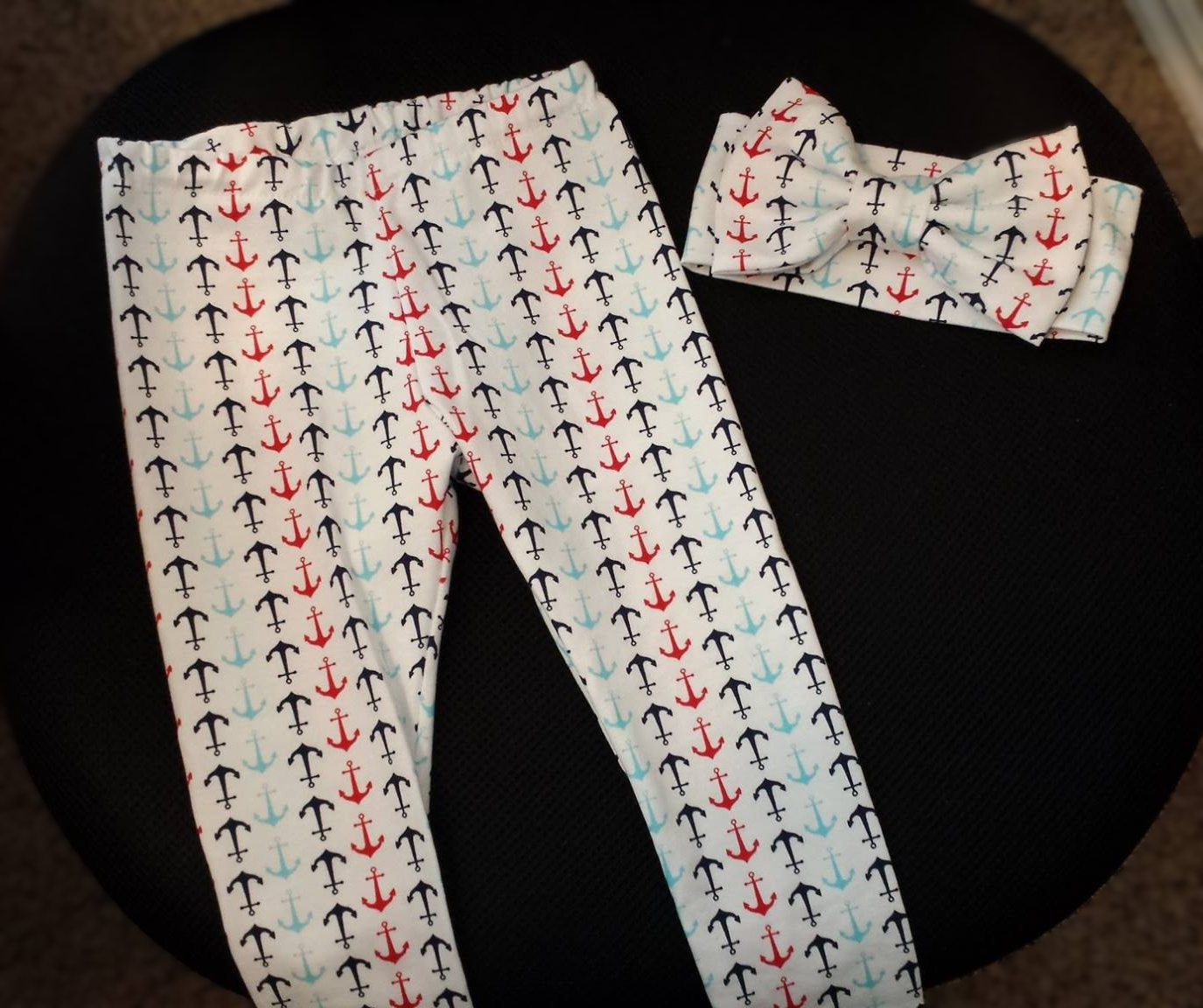 White leggings and a matching headband with a repeating pattern of navy, red, and light blue anchors on a black surface.