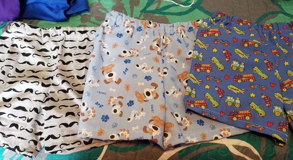 Three pairs of patterned boxer shorts—mustaches, dogs, and fire trucks—laid out on a green surface.