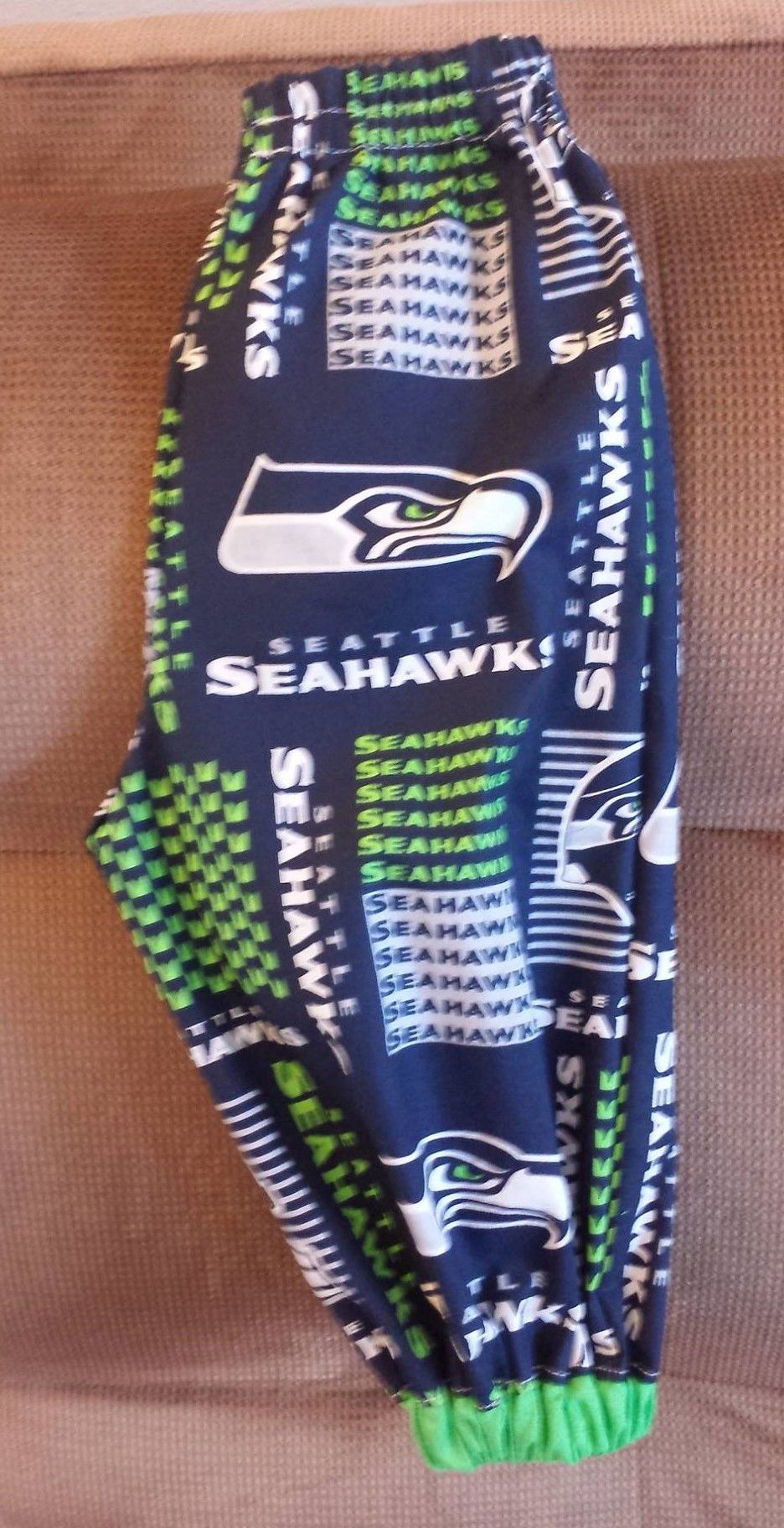 Navy blue Seattle Seahawks fleece pajama pants with a repeated logo and text pattern, featuring bright green cuffs.