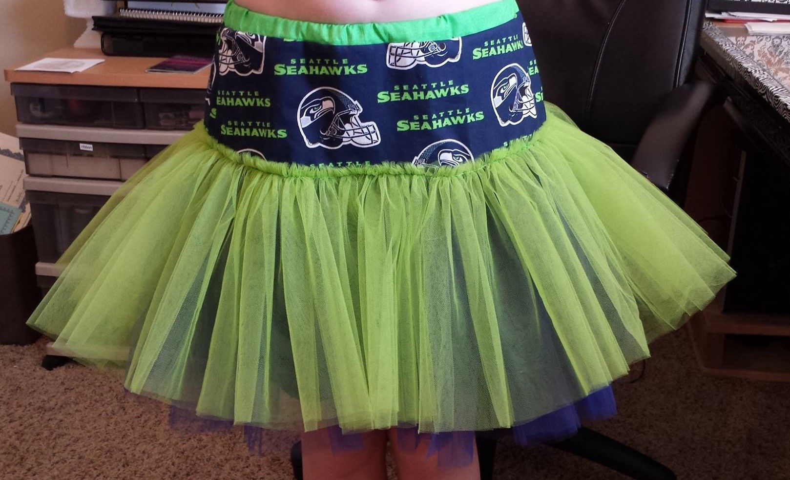 A lime-green tulle tutu with a patterned Seahawks waistband worn by a person.