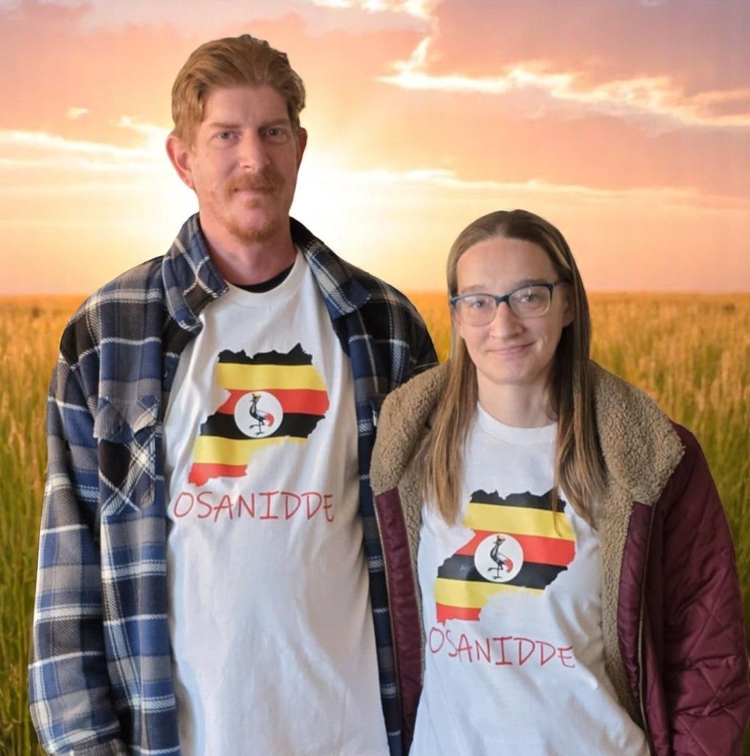 Two people stand in front of a field at sunset, both wearing white t-shirts with an outline of Uganda and the word 