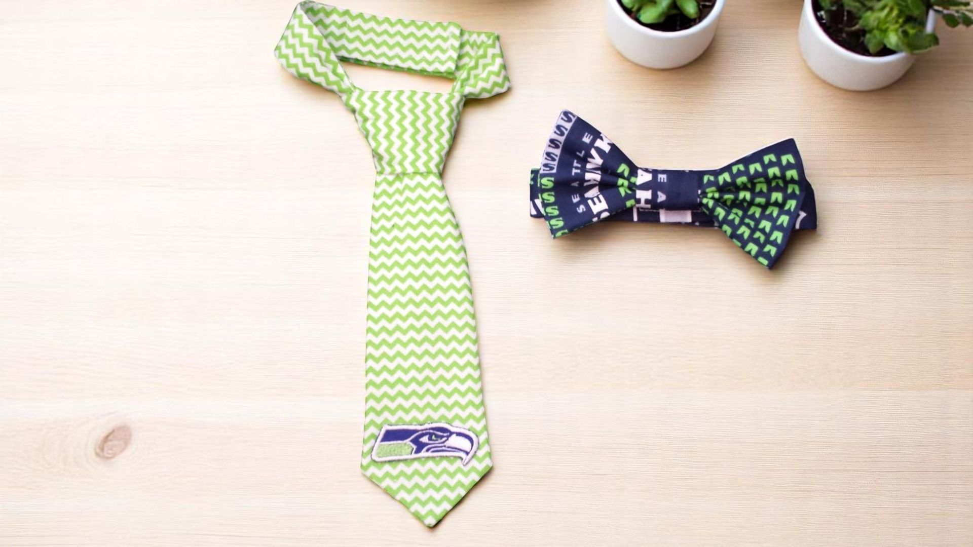 A Seahawks-themed lime green chevron tie and a navy blue patterned bow tie sit side-by-side on a light wood surface.