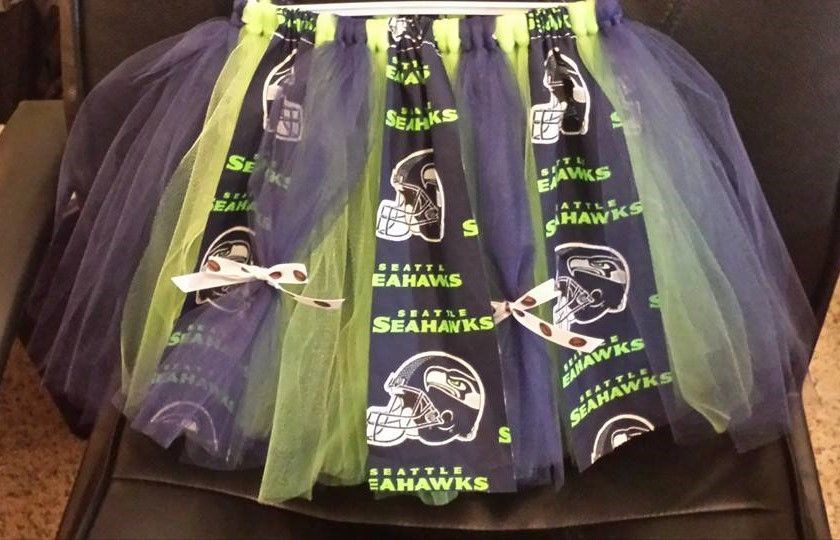 A Seattle Seahawks themed tutu made of navy fabric with team logos, interspersed with lime green and navy blue tulle.