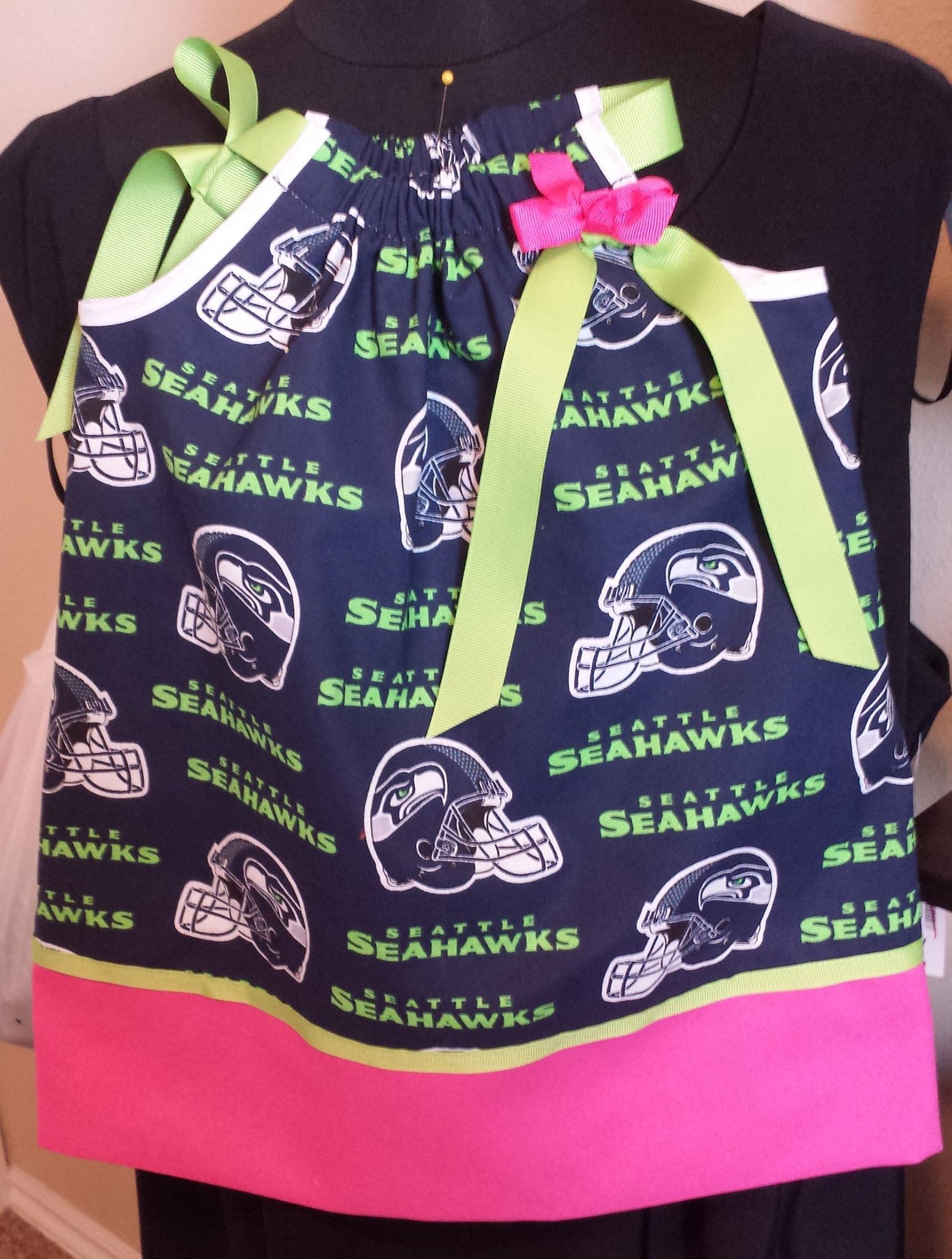 A navy blue dress with a Seattle Seahawks logo print, lime green ribbon straps, and a hot pink hem.
