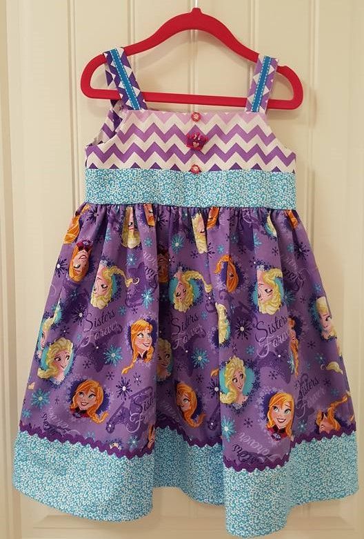 A girl's purple dress with a chevron bodice, Frozen character print skirt, and light blue patterned trim on a red hanger.