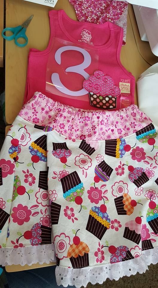 A bright pink tank top with a number three and cupcake design paired with a cupcake and floral print skirt with lace trim.