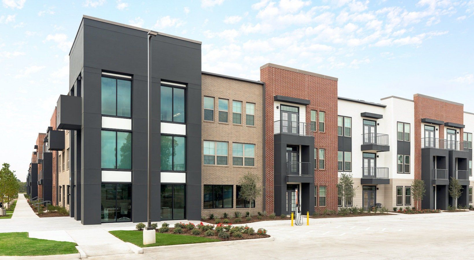Modern apartment building with brick, gray, and white facades.