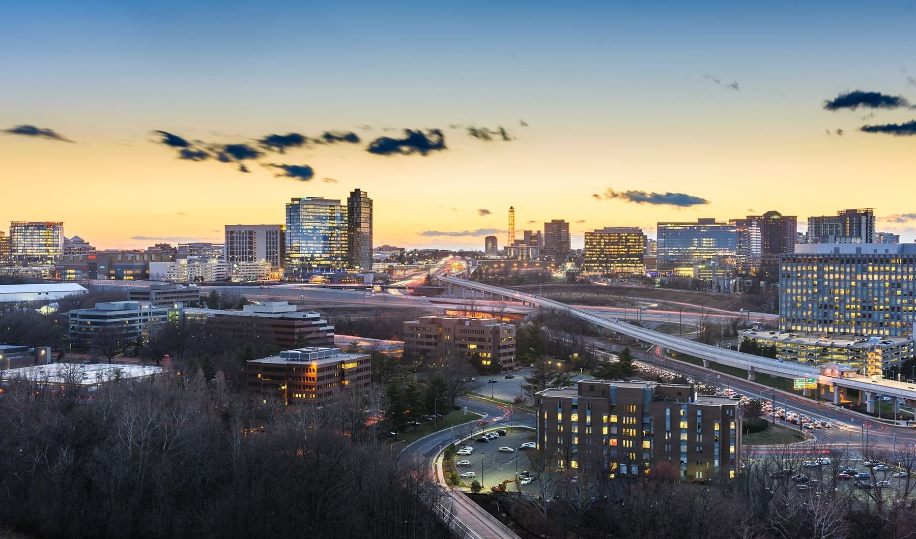 City skyline at dusk with buildings, roads, and a colorful sky.