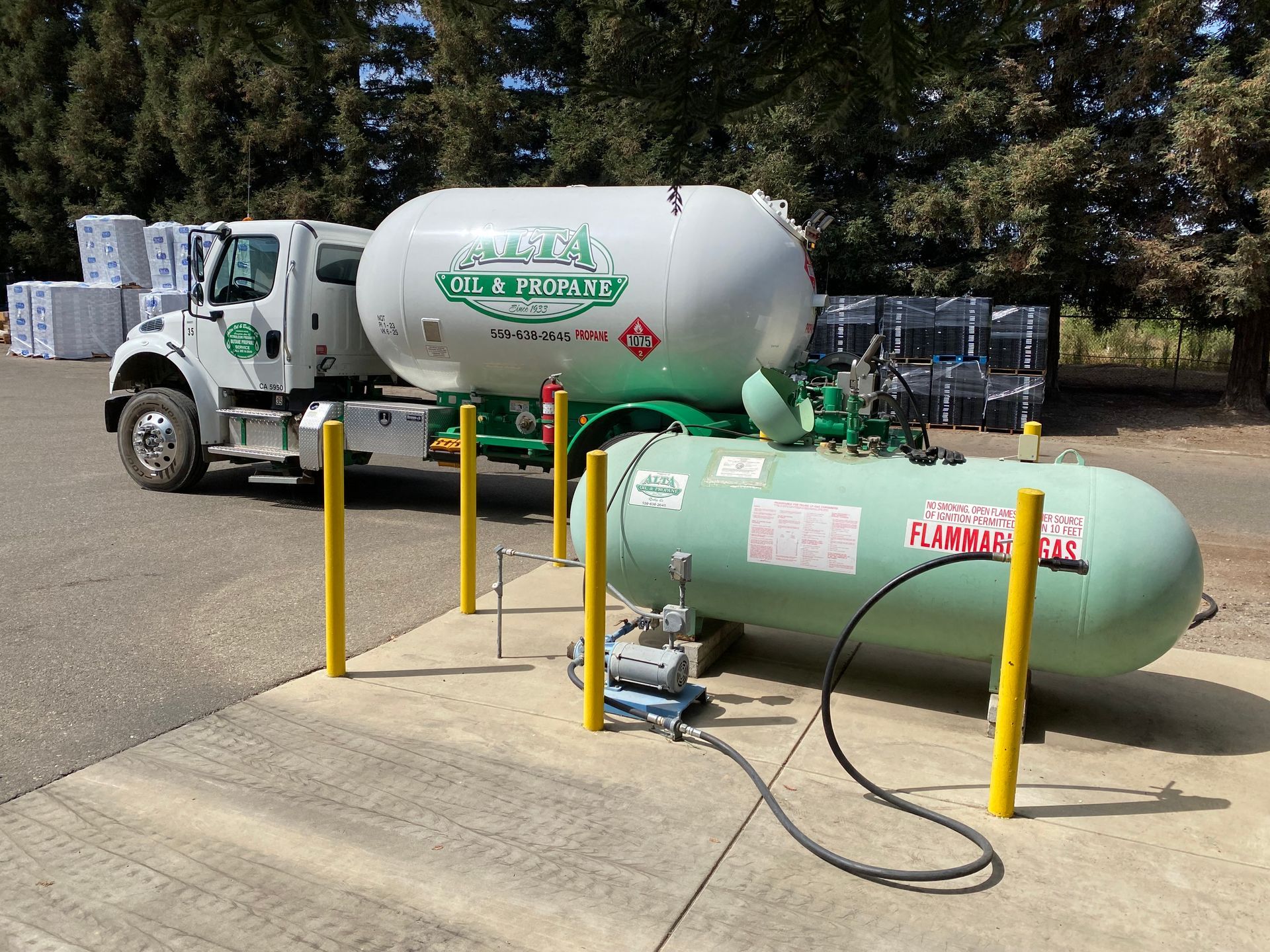 Green propane truck filling a green propane tank at a distribution center.