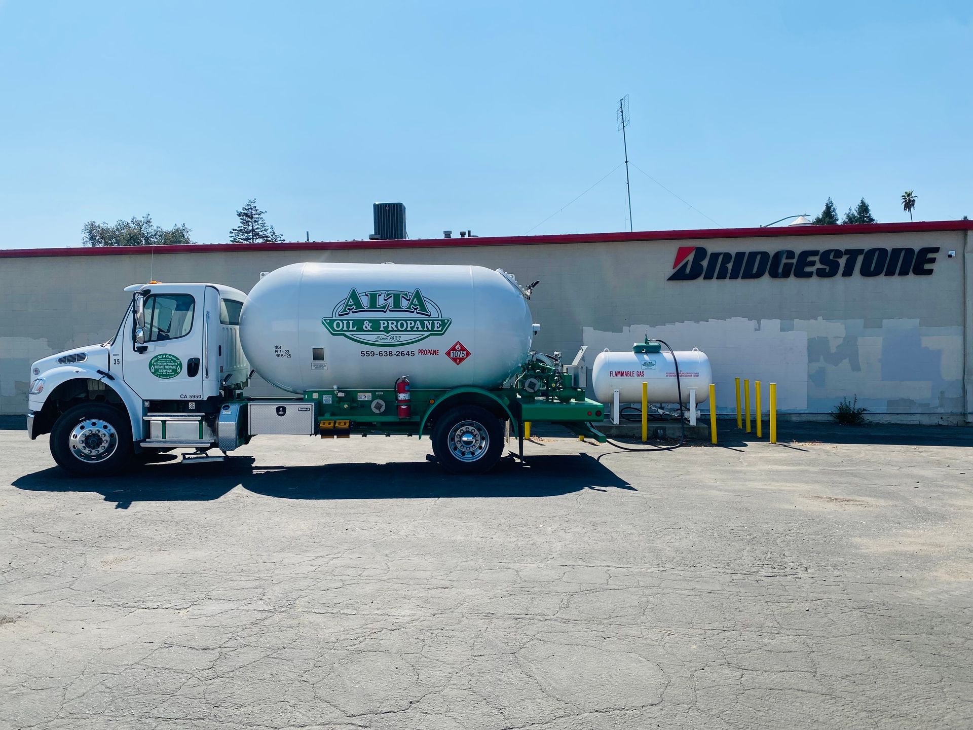 White propane truck parked outside a Bridgestone tire store on a sunny day.