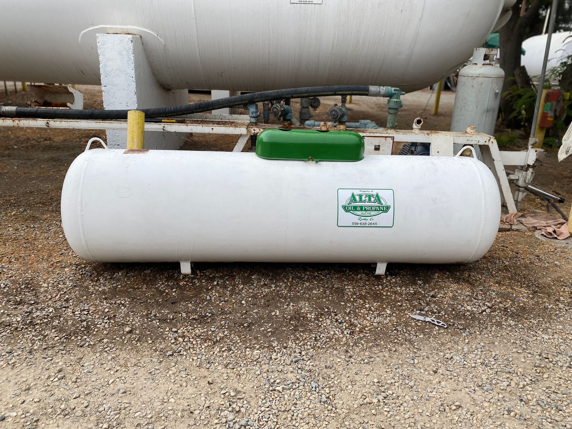 White propane tank on a gravel surface with green accents. ALTA logo on the side.