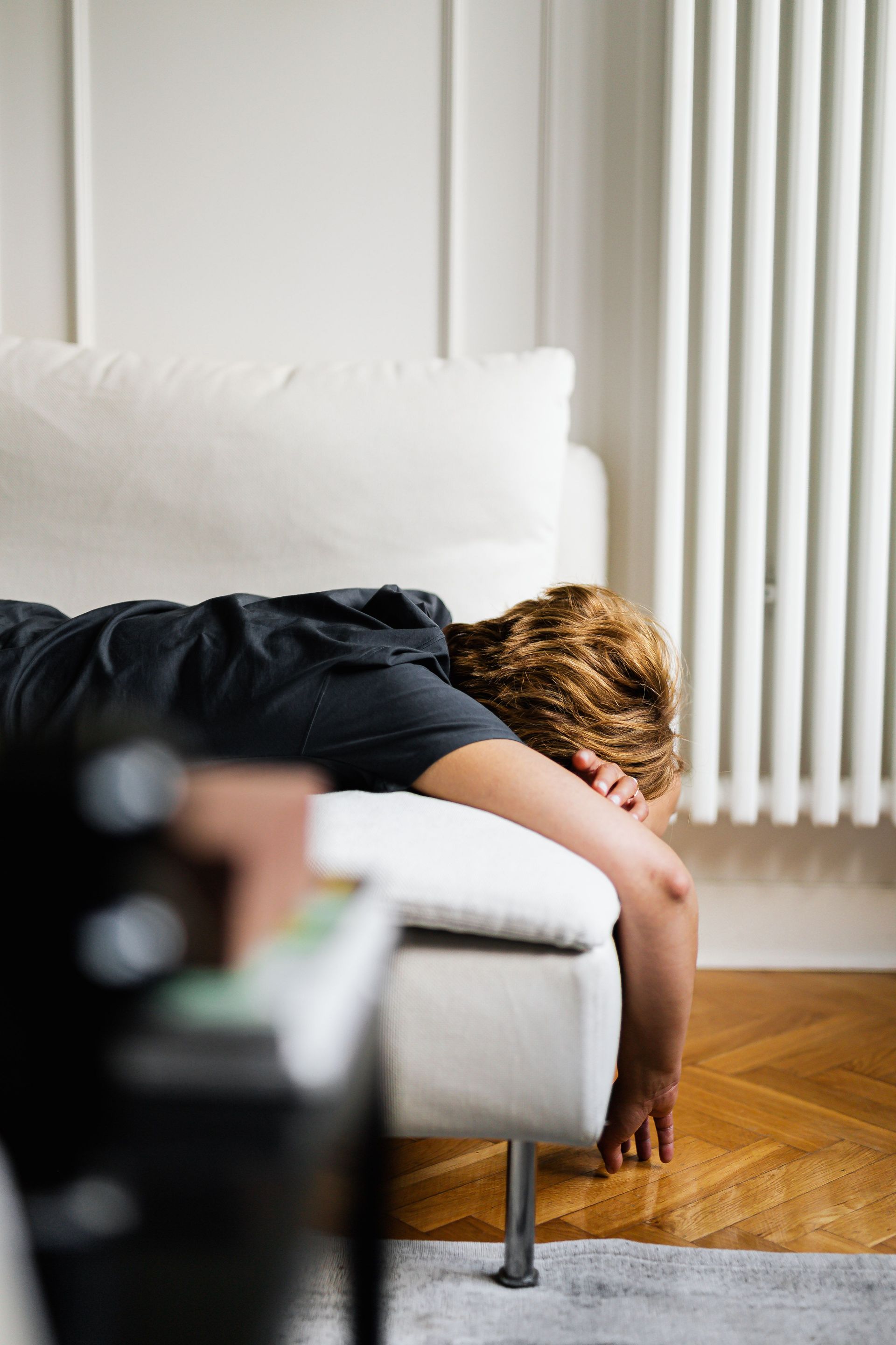 Person sleeping face down on a white couch in a bright living room
