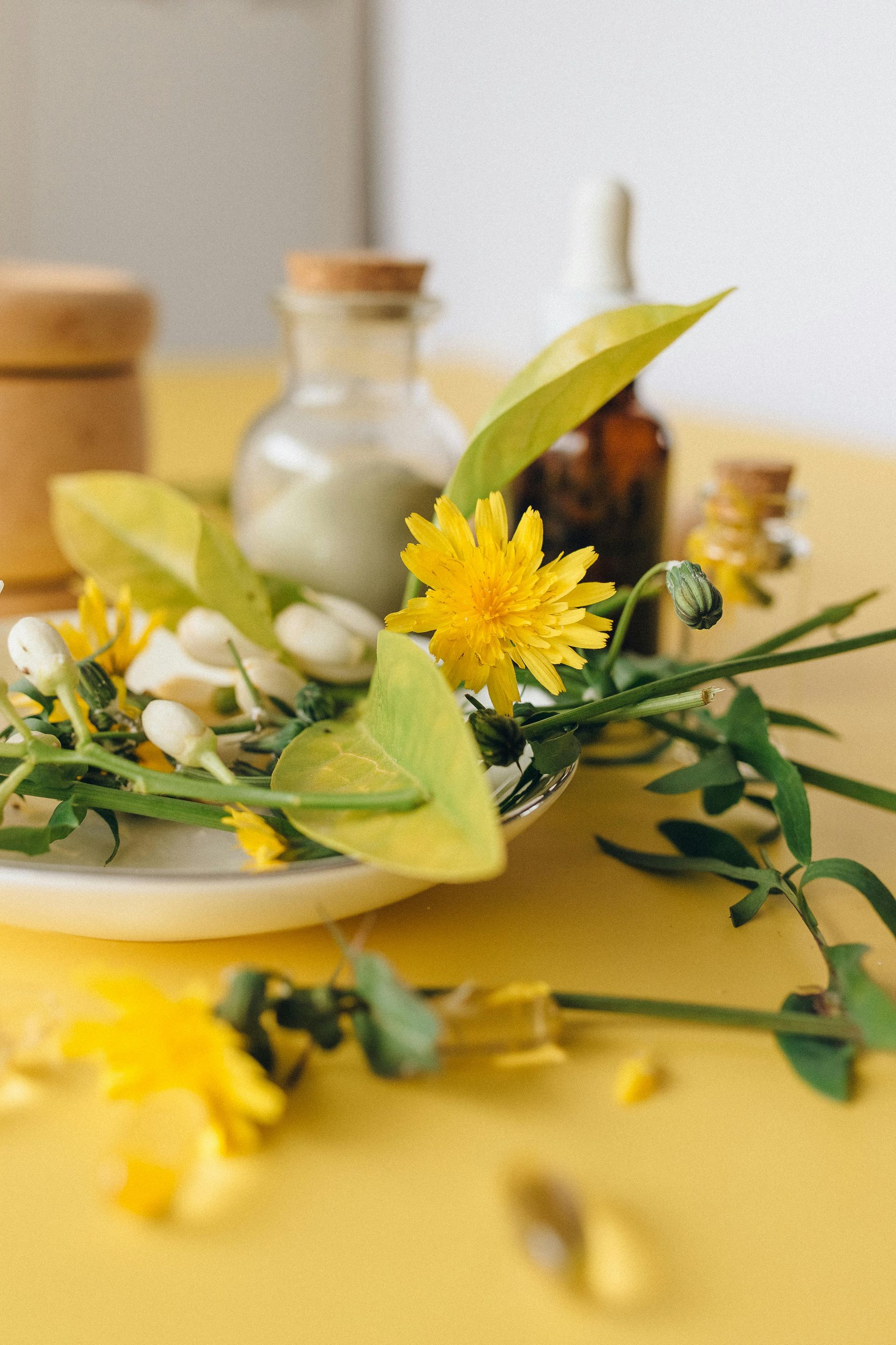 Yellow wildflowers on a yellow table with glass jars and a plate in soft focus
