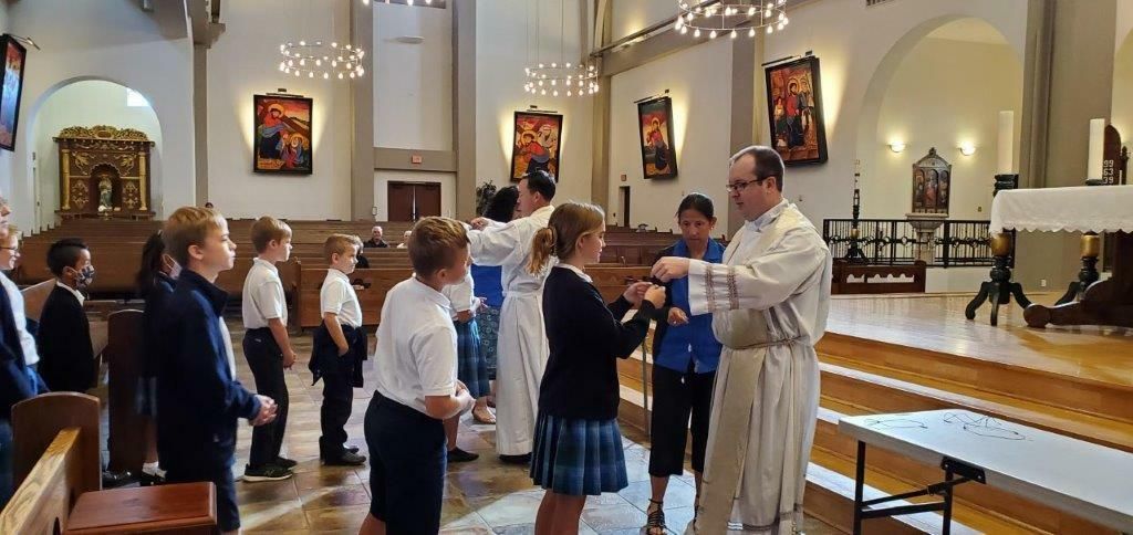 People receiving communion in a church, with a priest at the altar.