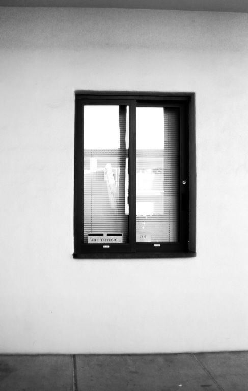 Black-framed window in a plain white wall, with a dark floor at the bottom.