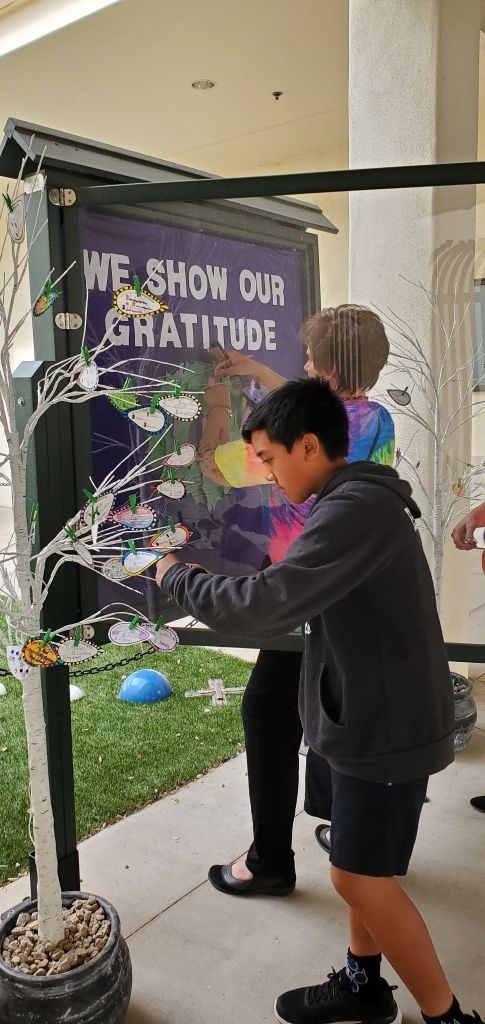 Child touches a purple, flower-decorated display board outdoors under a canopy.