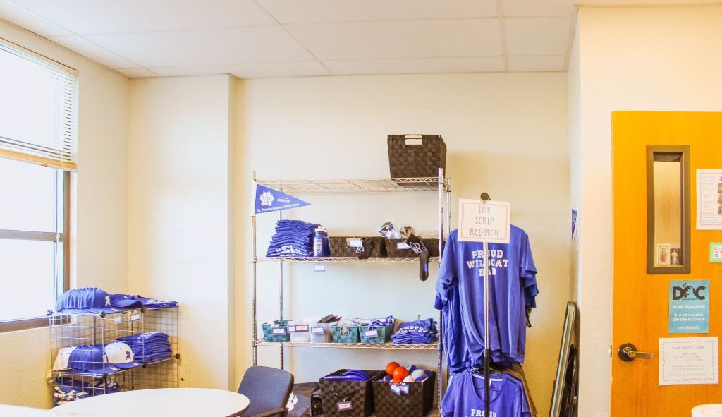 Small room with shelves of blue items, hanging clothes, and a bright orange door.