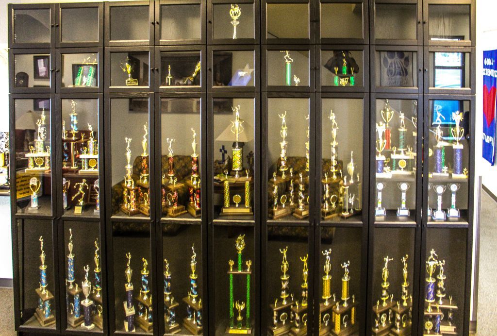 Glass cabinet filled with gold and silver trophies and awards on display