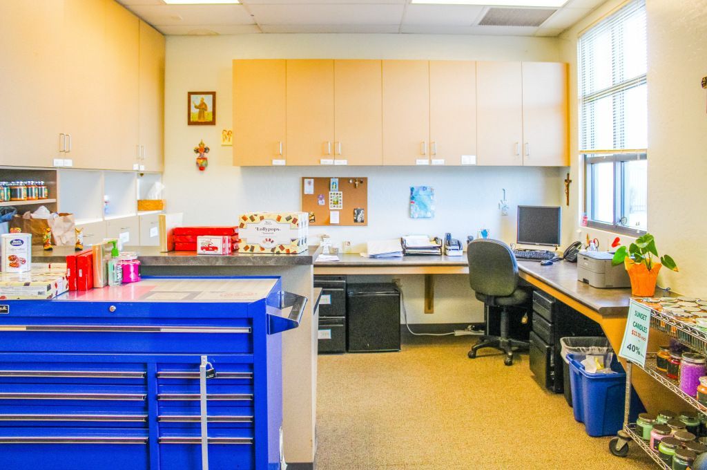 Bright office or lab room with blue storage cabinets, desk, chairs, and large windows