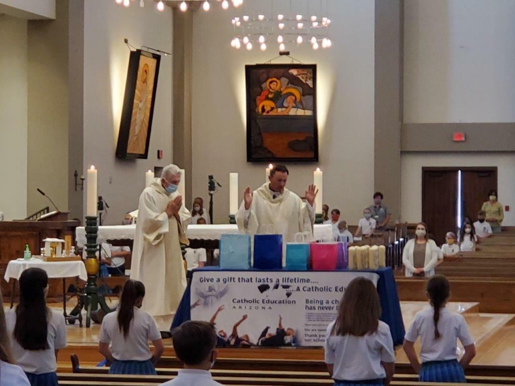 Church altar service with two clergy in white robes, seated congregation, and religious icons on the wall