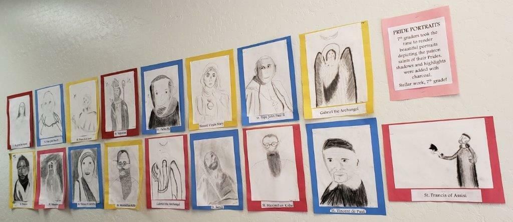 Colorful classroom wall display of framed student-style portraits and drawings on pink paper.