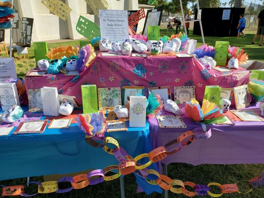 Colorful memorial display with flowers, notes, candles, and paper chains on a table outdoors