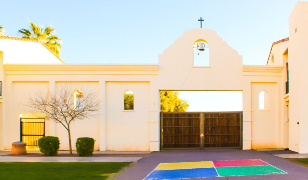 White church-like building with a cross, arched entrance, and a colorful painted walkway in front