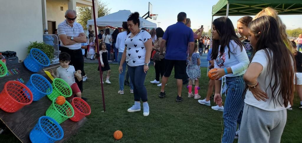 People standing outdoors around a colorful lawn game with circular targets and an orange ball.