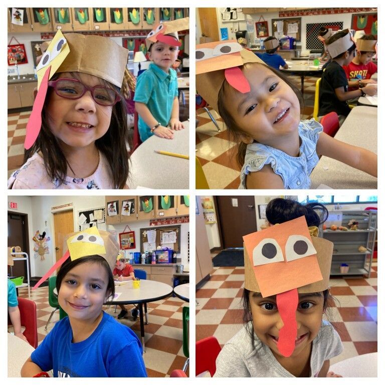 Children in a classroom wearing colorful paper hats and smiling at the camera.