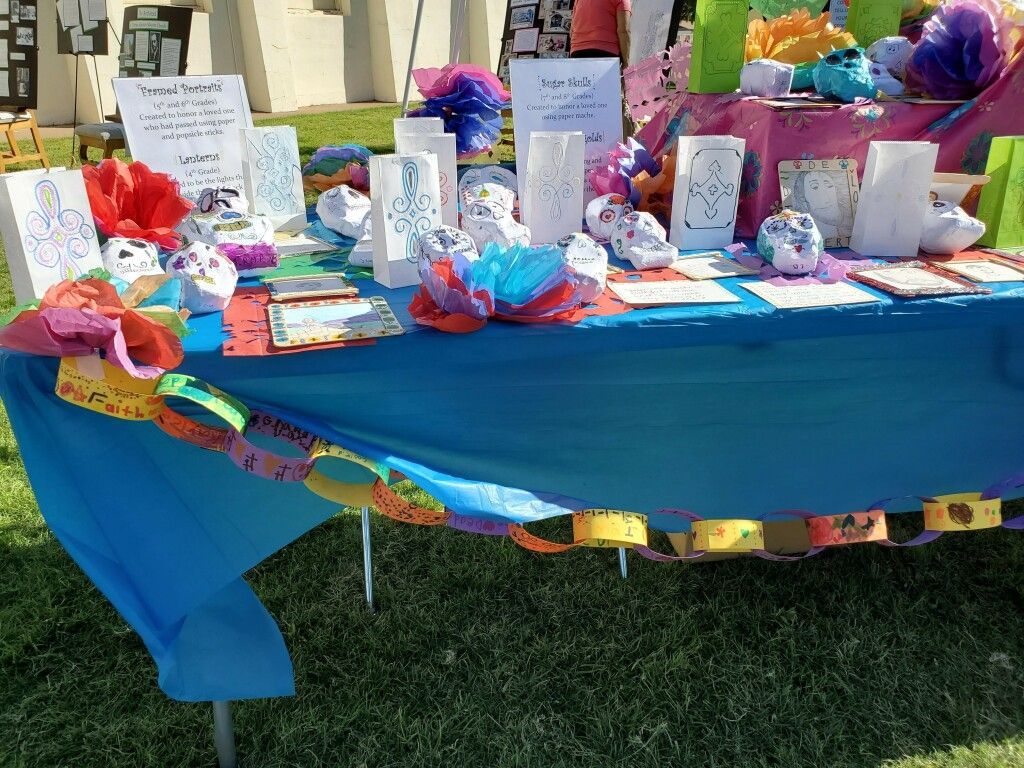 Colorful memorial table with cards, flowers, and ribbons draped in bright blue cloth outdoors
