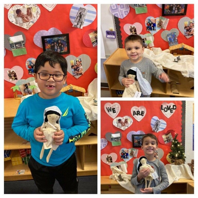 Children holding stuffed animals in front of a red heart-themed classroom display.