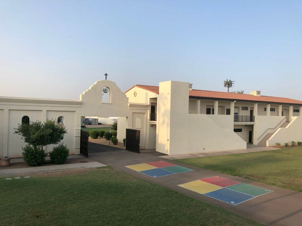 Apartment complex entrance with a colorful tiled walkway and green lawn under a clear sky
