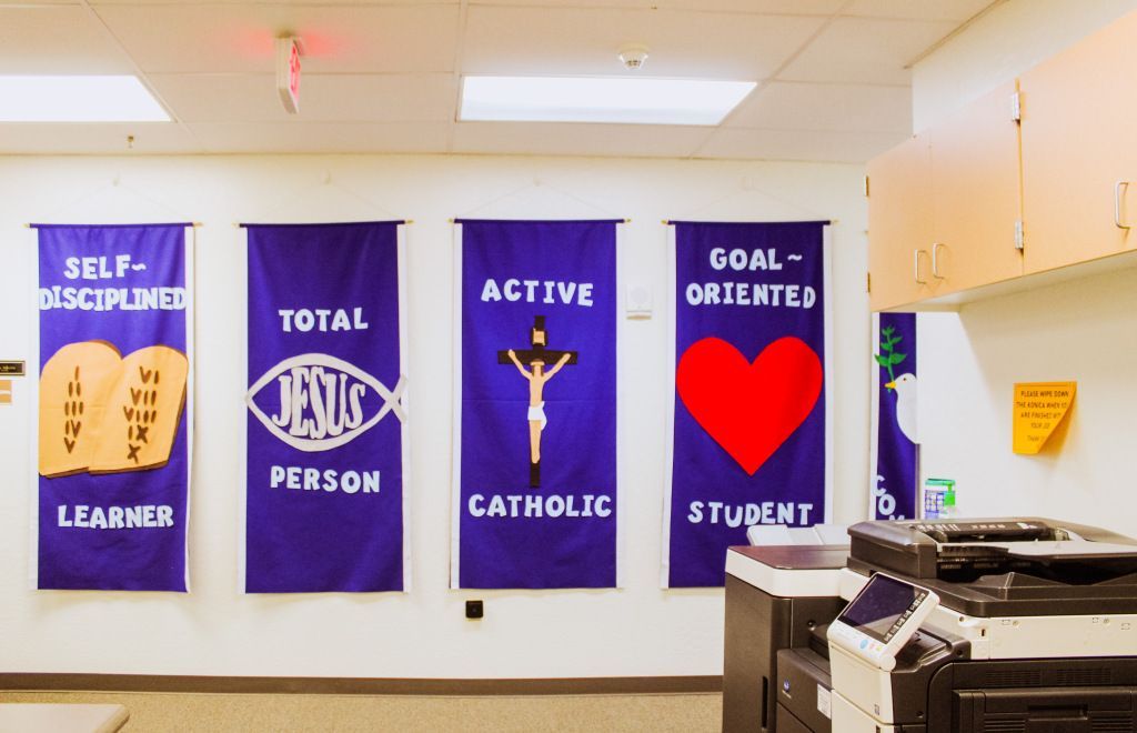 School hallway with purple banners reading self-disciplined, total person, active Catholic, and goal-oriented student.