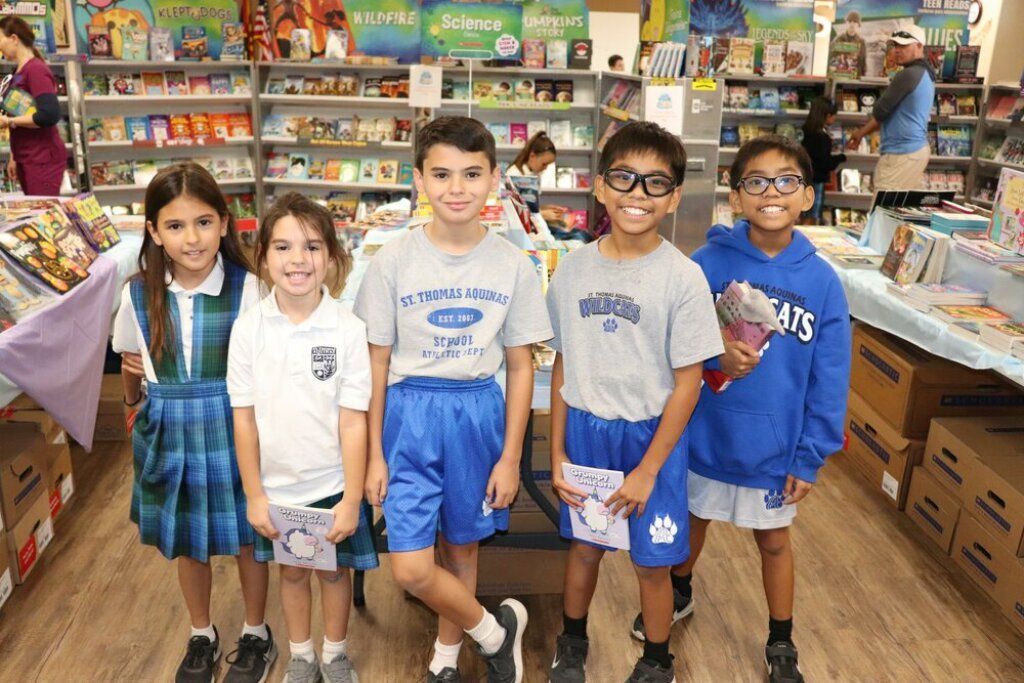 Five children stand in a grocery store aisle, posing in front of shelves and produce displays.