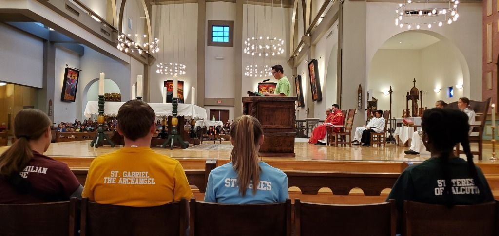 People seated in a church pew during a service, facing the altar and choir.