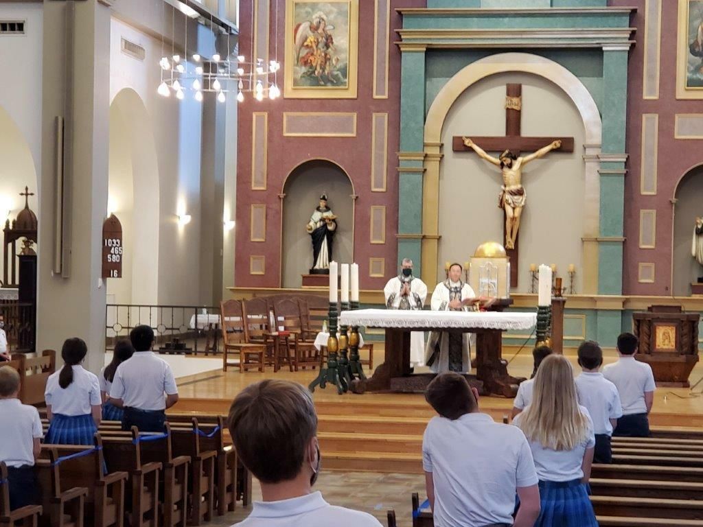 Church interior with altar, crucifix, and a congregation seated in pews during a service