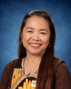 Smiling woman in a brown top against a blue studio backdrop