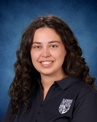 Smiling person in navy patterned top against a blue studio backdrop
