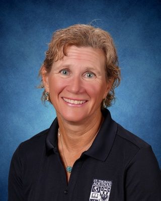 Smiling person in a navy shirt against a blue studio backdrop.