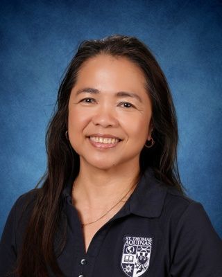 Portrait of a smiling person in a white shirt against a blue studio background