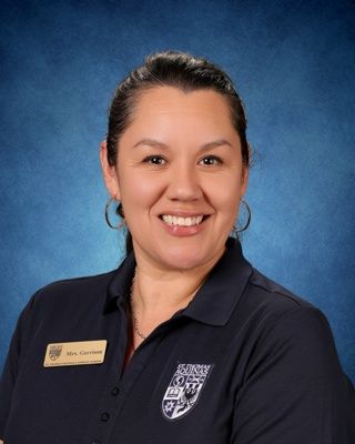Smiling person in a navy top against a blue studio background