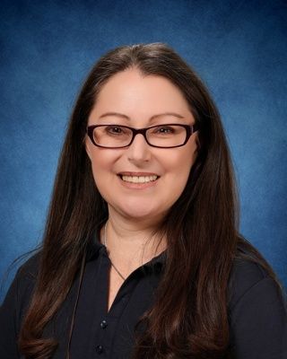 Smiling woman in a red blouse against a blue studio backdrop
