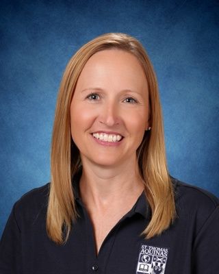 Smiling woman in a white blouse against a blue studio backdrop
