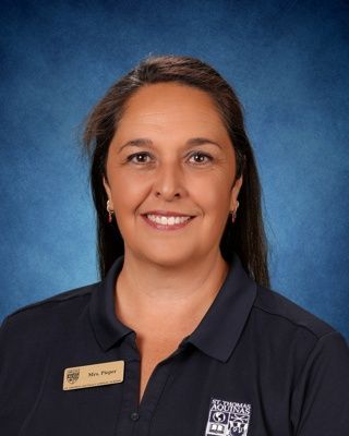 Portrait of a smiling woman with dark hair against a blue studio background