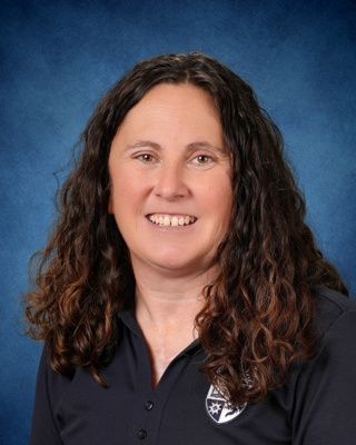 Head-and-shoulders portrait of a smiling person in a navy blouse on a blue studio background