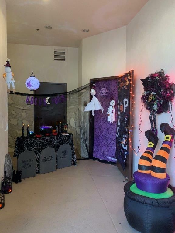 Halloween-decorated entryway with cobwebs, skeletons, spooky lights, and a witch hat decoration